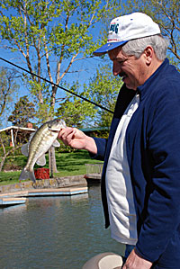 Rick Dykstra with a bass caught under a dock. The best docks are those that start shallow and end at the edge of a drop-off in 8 or 10 feet of water. Bass have easy access to the dock that way and can migrate from deeper to shallow water without moving very far.