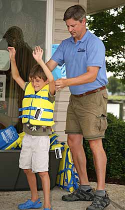 Buying a life jacket that your child can grow into is a big mistake, says BoatUS. This child's life jacket doesn't move up over his ears when gently lifting - a good fit.